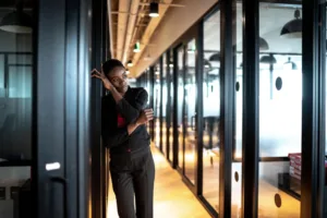 Manager hésitant devant le bureau d'une collaboratrice avant une conversation importante.